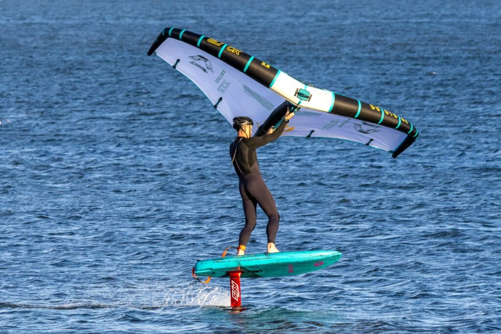 Wingfoiler naviguant sur l'eau avec sa voile, aile de wing gonflée en action